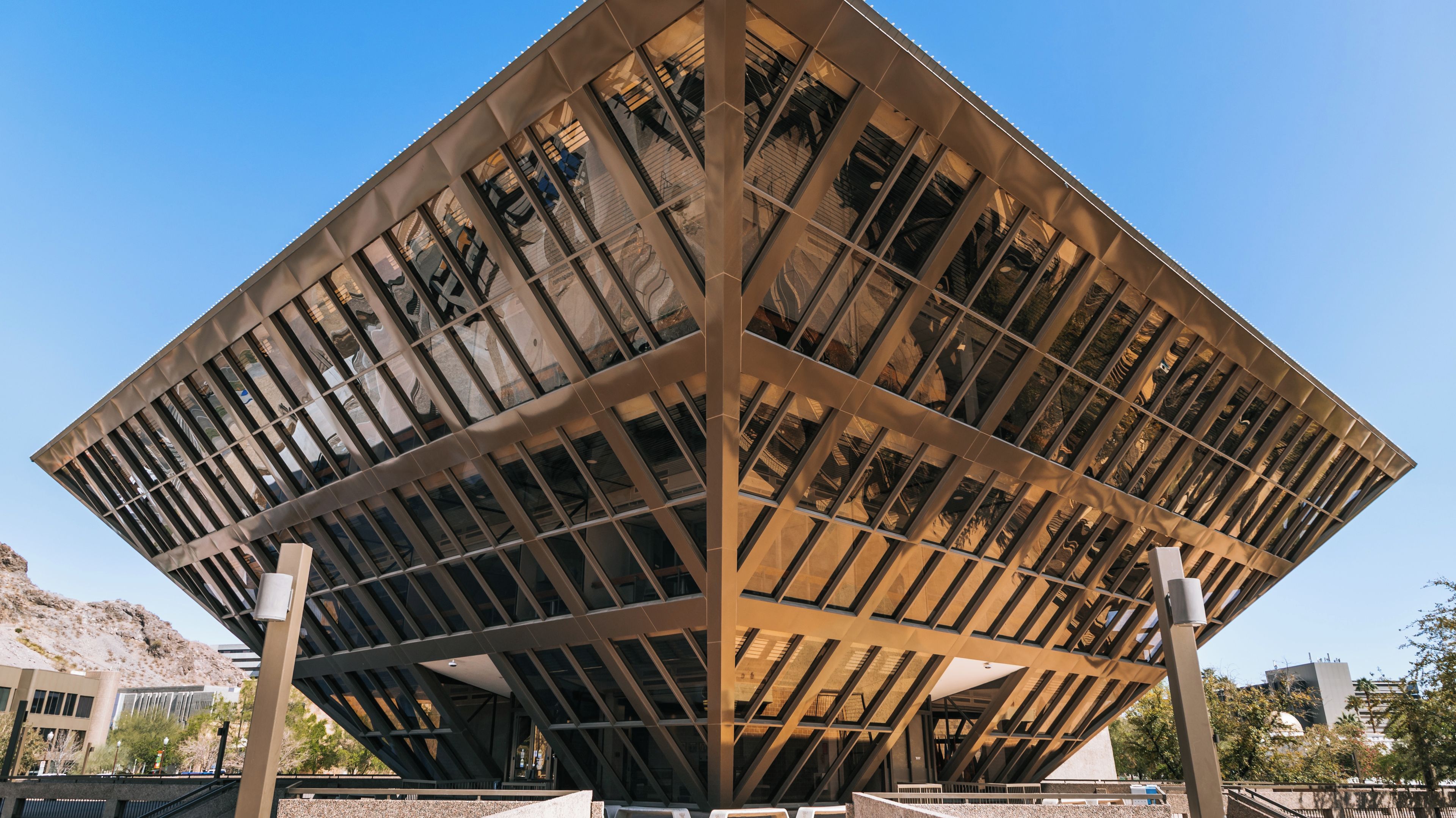 Uma estrutura arquitetônica moderna com design geométrico, destacando uma seção central imponente e diversas colunas de suporte.