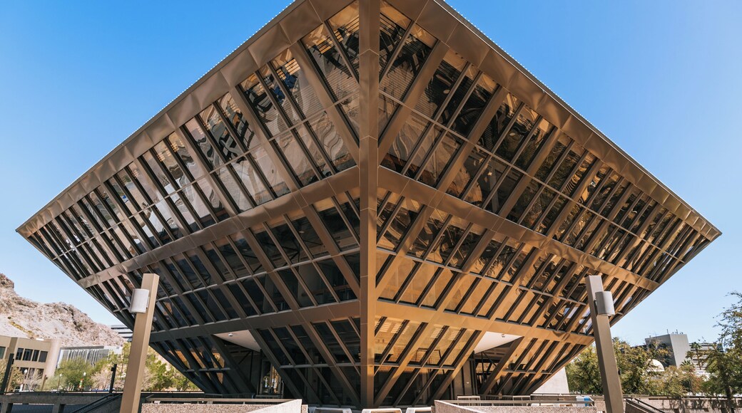 Uma estrutura arquitetônica moderna com design geométrico, destacando uma seção central imponente e diversas colunas de suporte.