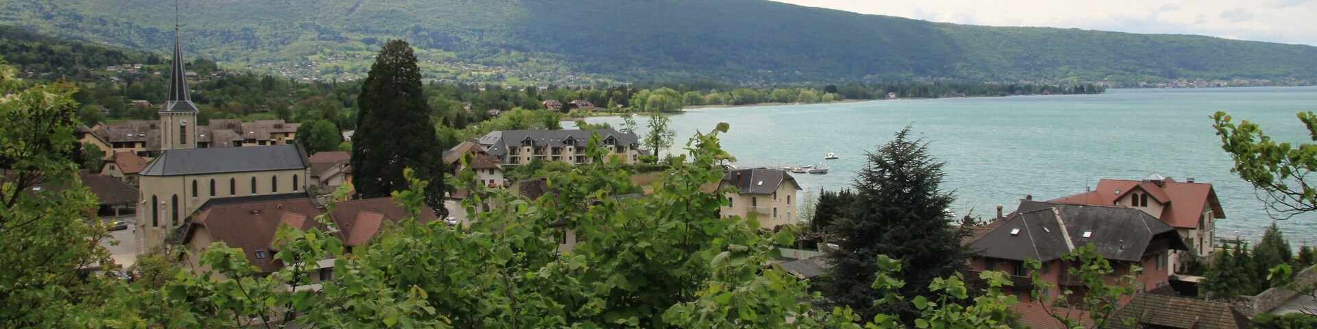 Un pueblo con una iglesia, casas y un lago rodeado de montañas.