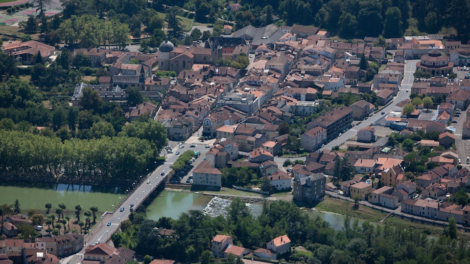 An aerial view of a historic town with a river, a bridge, and a prominent church with a dome.
