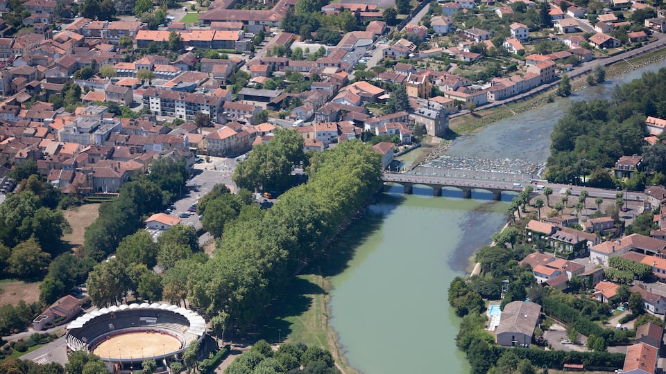An aerial view of a town with a river, a bridge, and a stadium.