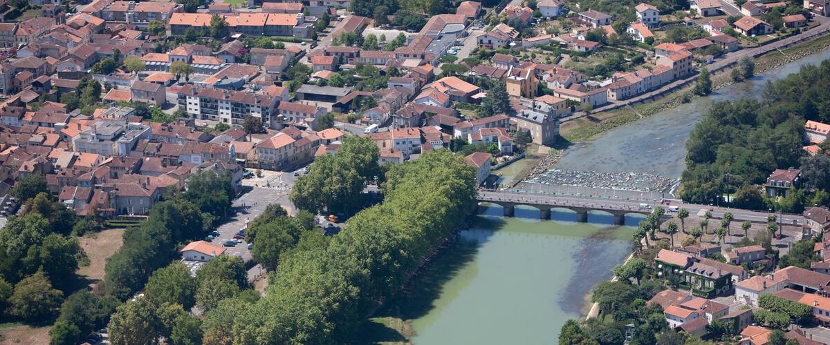 An aerial view of a town with a river, a bridge, and a stadium.