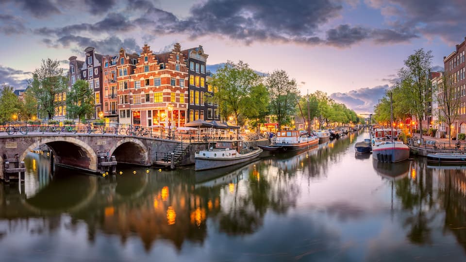 Amsterdam. Panoramic view of the downtown of Amsterdam. A blue evening time and the serene reflection of lights in the water. Europe, Netherlands, Holland, Amsterdam.