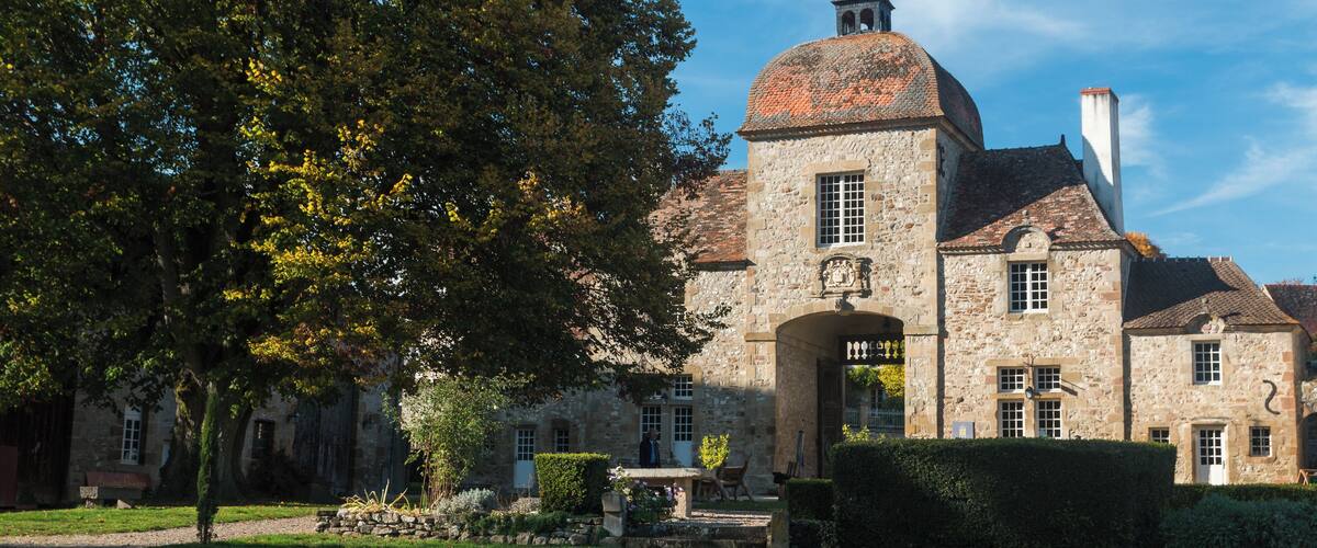 A historic stone building with a dome and bell tower, surrounded by lush greenery and a well-maintained lawn.