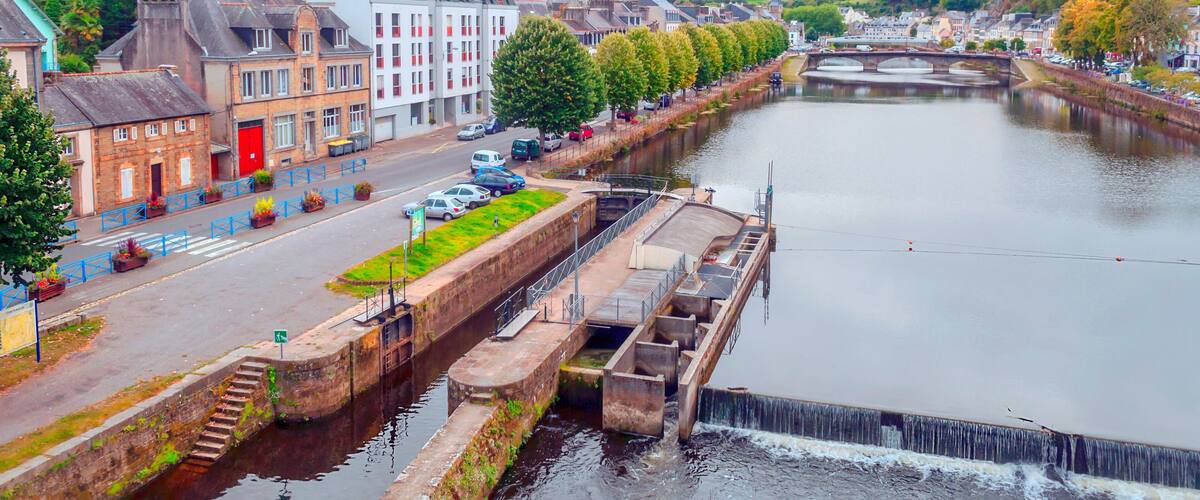 A river with a lock system, a bridge, and buildings along the riverbank.