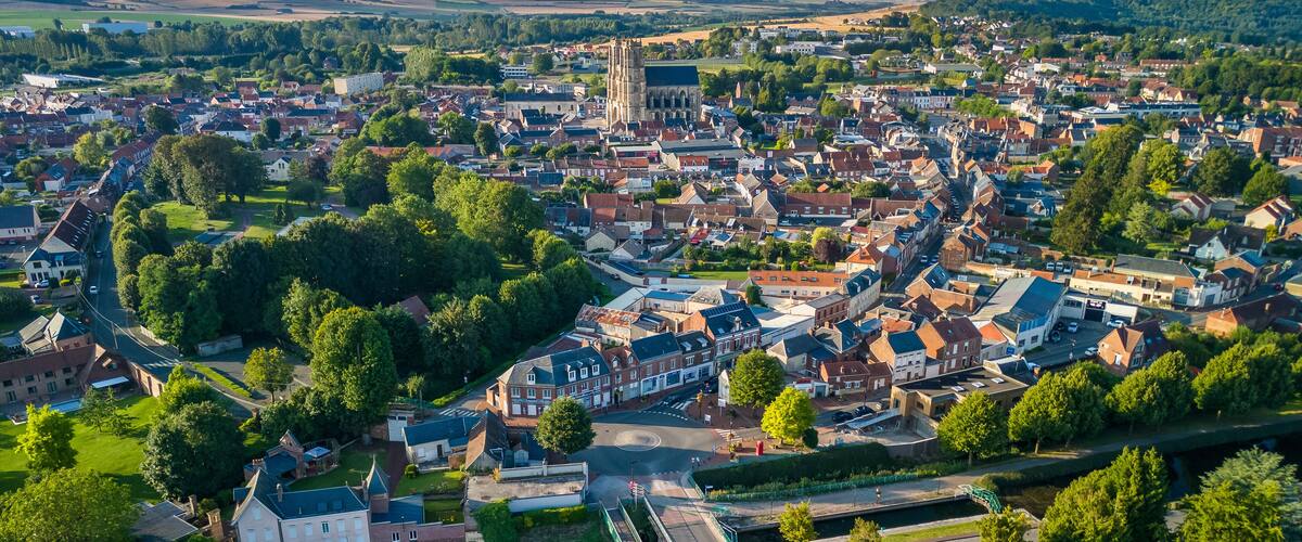 An aerial view of a town with a prominent church, green spaces, and residential areas.