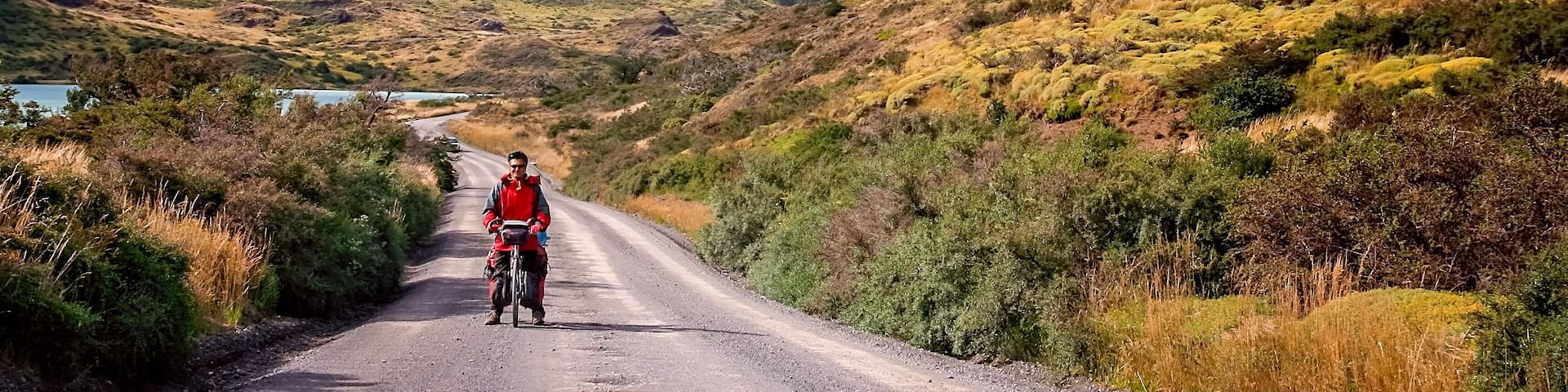 A cyclist on a road with mountains in the background.