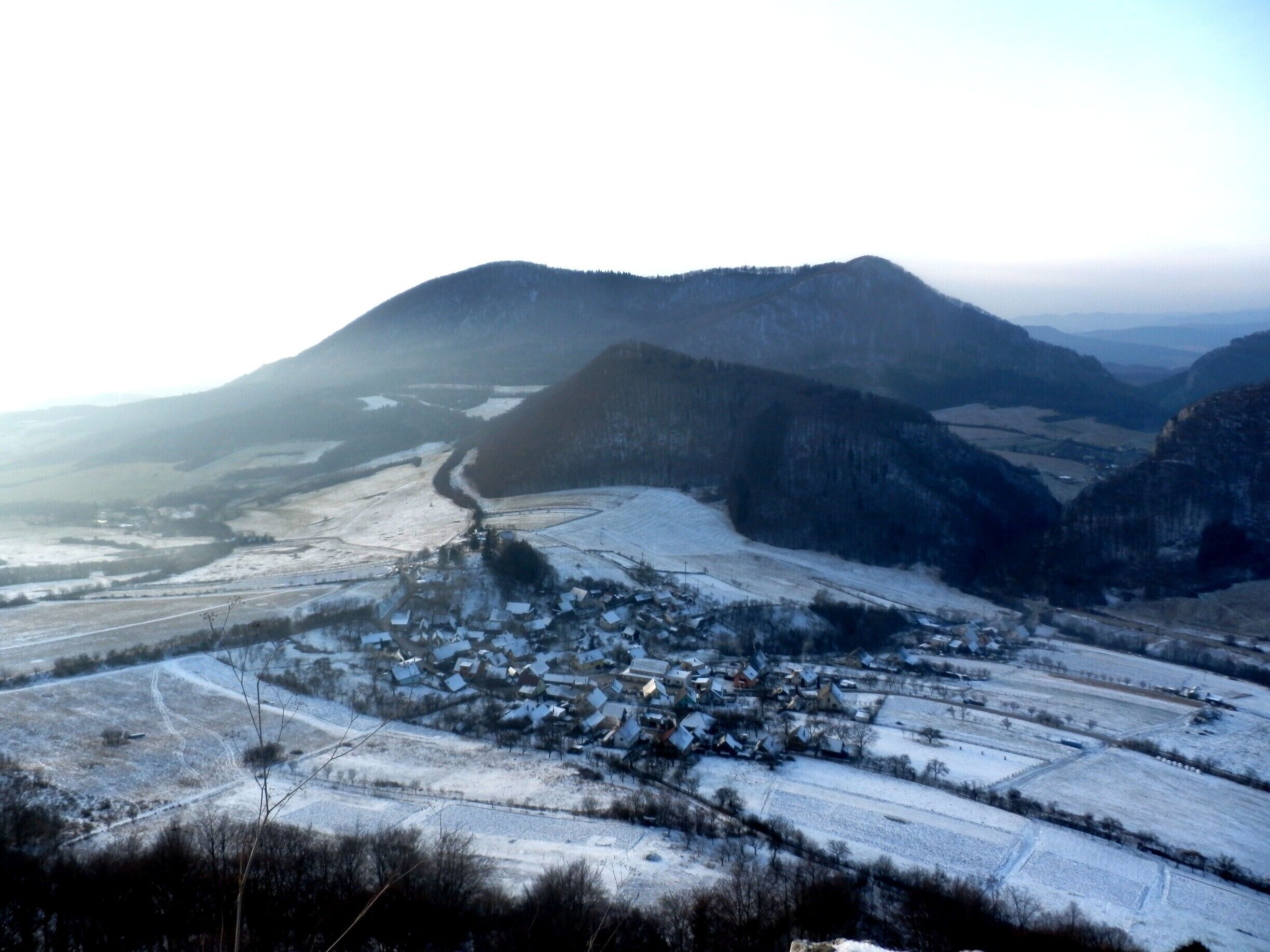 A snow-covered village nestled in a valley with mountains in the background.