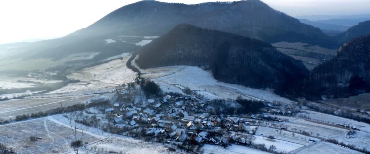 A snow-covered village nestled in a valley with mountains in the background.