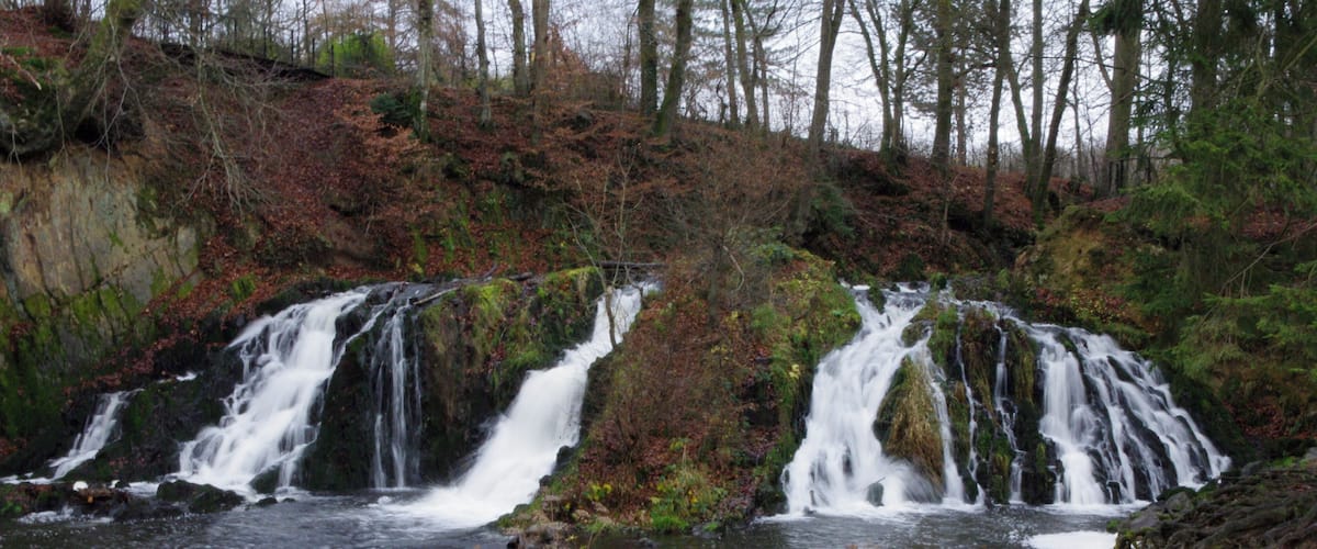 A waterfall cascading over rocks in a forested area.