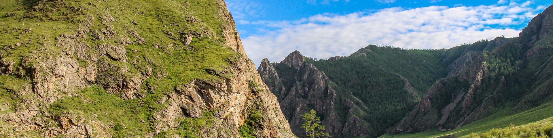 Un río serpentea a través de un paisaje montañoso con acantilados rocosos y vegetación verde.