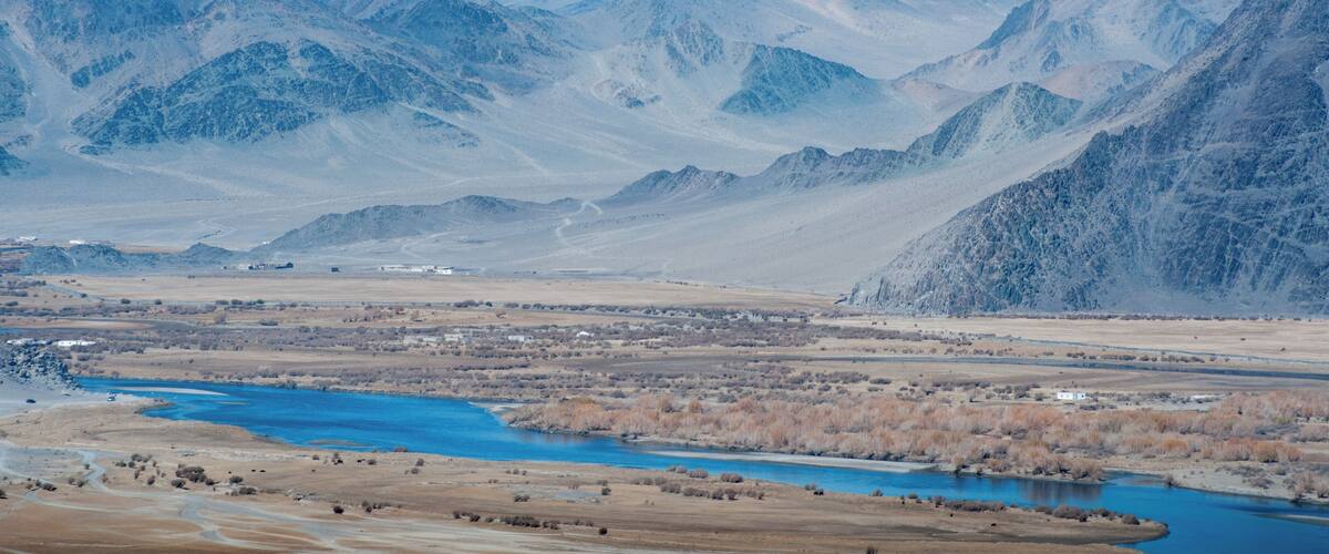 A mountainous landscape with a river and sparse vegetation.