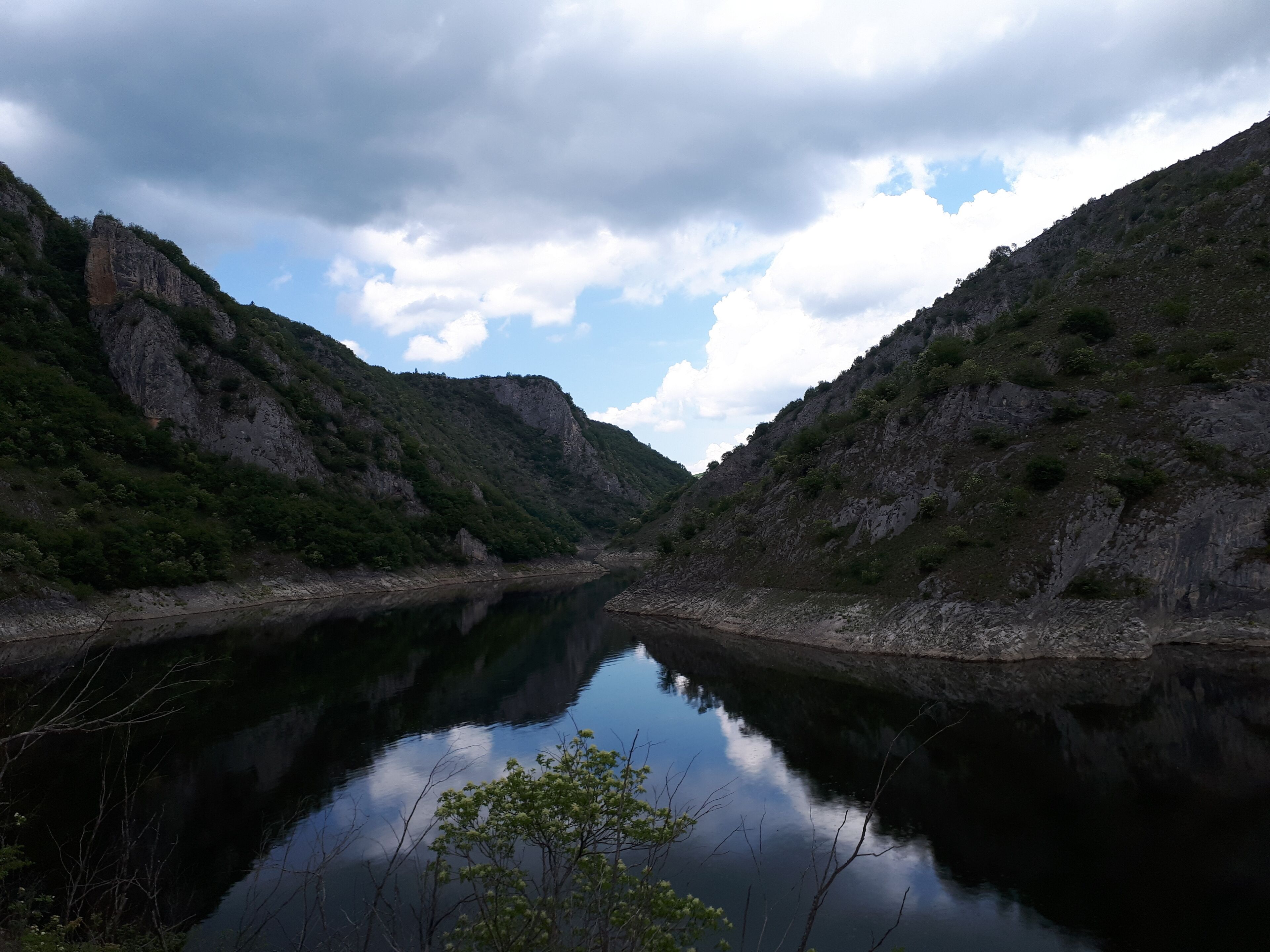A calm river reflecting the surrounding cliffs and sky.