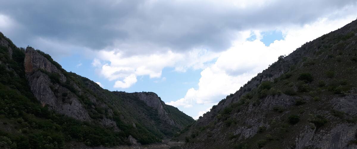 A calm river reflecting the surrounding cliffs and sky.