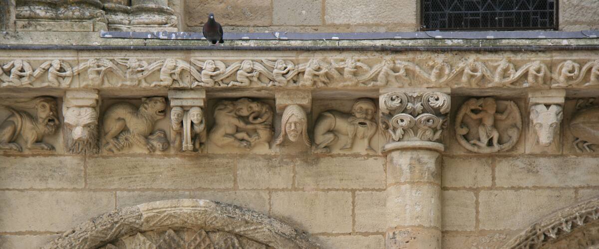 A stone facade with intricate carvings of mythical creatures and circular arches.