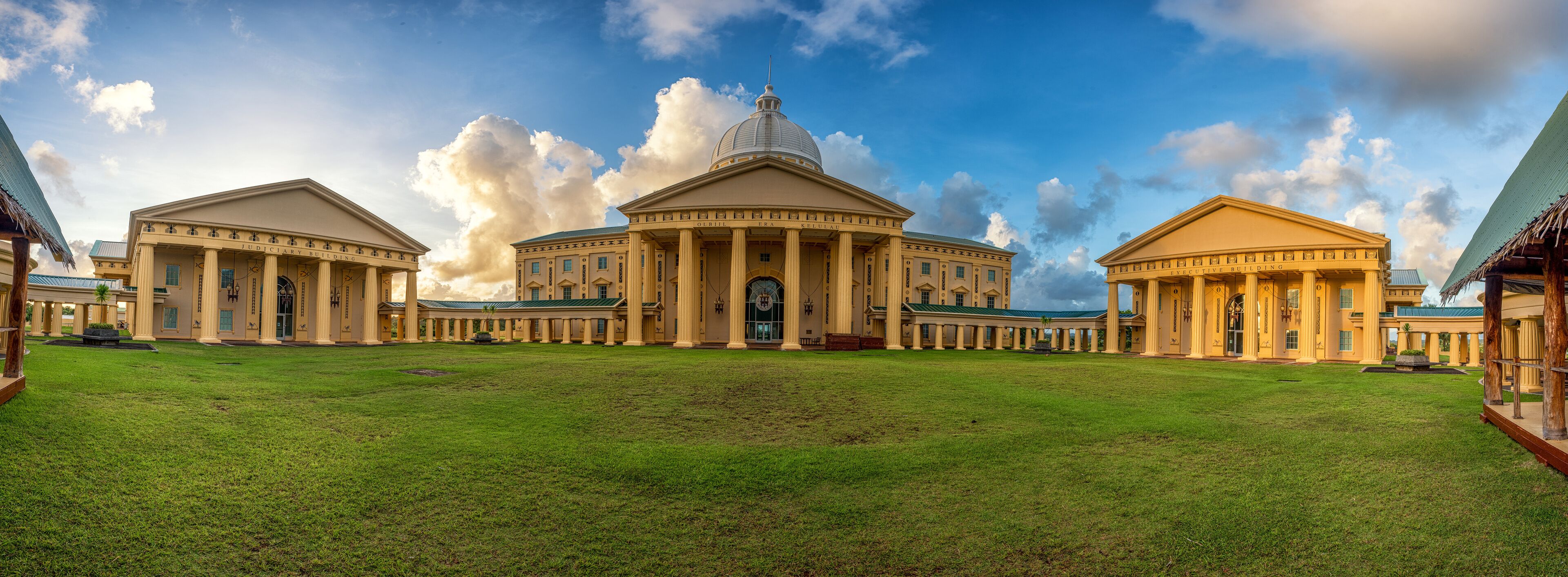 A grand building with a large dome and columns, surrounded by a well-maintained lawn.