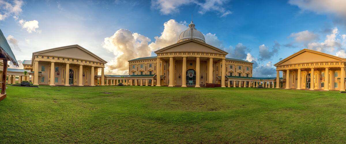 A grand building with a large dome and columns, surrounded by a well-maintained lawn.
