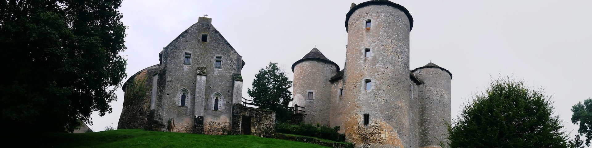 A historic stone castle with multiple towers and a grassy hill.