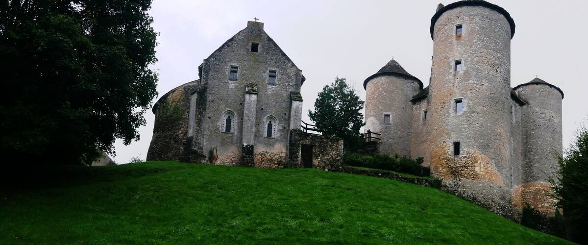 A historic stone castle with multiple towers and a grassy hill.