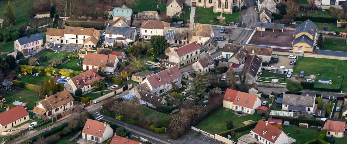 An aerial view of a small village with a prominent church, residential houses, and green spaces.