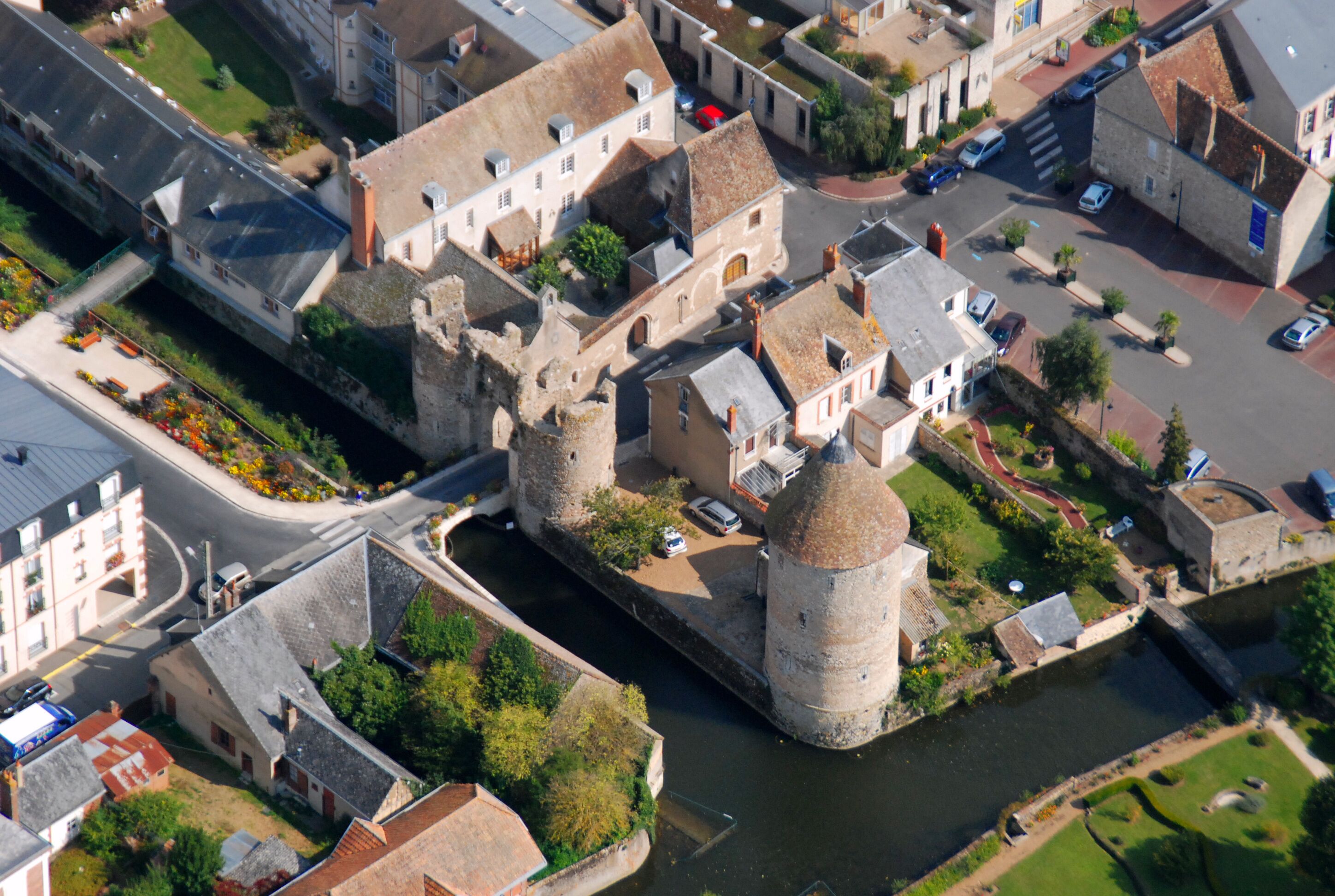 An aerial view of a historic town with a prominent tower, narrow streets, and a river.