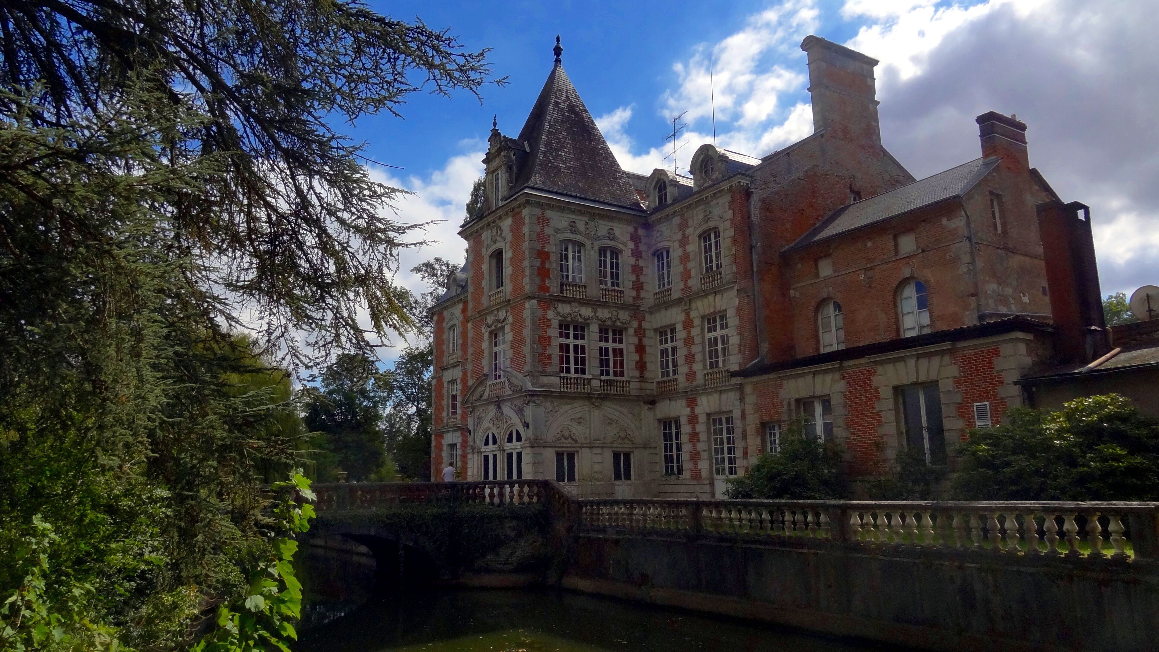 A historic building with a prominent tower and a bridge over a canal.