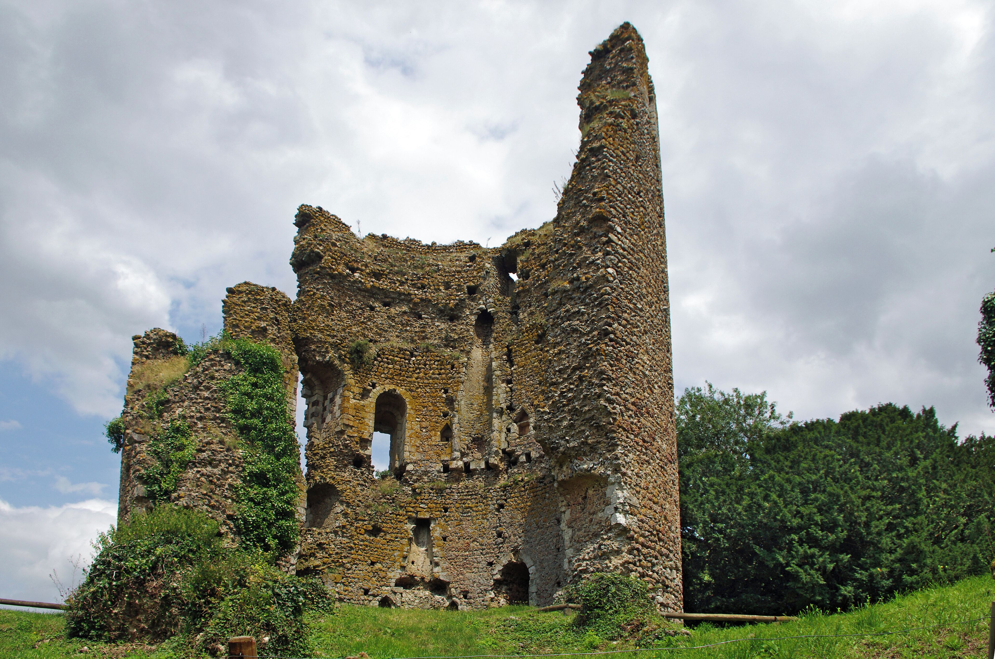 Fréteval (Loir-et-Cher) Le château féodal de Fréteval. Le donjon. Il est construit au point culminant du plateau qui domine le Loir. Le donjon est directement assis sur le sol naturel. La construction du donjon est voisine de 1090 et la date de destruction du donjon proche de 1428-1429. Un examen approfondi montre que le donjon a été construit d'un seul jet. Architecture du donjon. Innovation pour l'époque, le donjon est cylindrique. Le diamètre à la base est de 15,60 mètres. Sa hauteur de 27,50 mètres, y compris 1,50 mètre de fondations. Les matériaux sont tous d'origine locale ou proche : silex, poudingue, grison*, craie tuffeau et calcaire de Beauce. Le liant est un mortier de chaux. La couverture était vraisemblablement de bardeaux de bois à l'origine, puis de tuiles. La muraille est en maçonnerie fourrée*. La construction a été réalisée à l'aide d'échafaudages successifs posés sur des boulins* engagés dans des trous dans la murailles. On observe seize rangée de trous de boulins espacées d'environ 1,10 mètre. L'alignement vertical des trous de boulins amène une faiblesse de la muraille. Le donjon comprend quatre niveaux: Le rez de chaussée, complètement aveugle avec un sol de mortier posé sur le sol naturel. Le premier étage avec la porte d'accès, éclairé par quatre fenêtres. Le premier étage copossède une cheminée murale et un puits. Le deuxième étage, avec deux fenêtres qui subsistent. Une cheminée murale. Une galerie externe ceinturait cet étage qui devait être l'étage seigneurial. Une porte externe permet l'accès à la galerie. Le troisième étage, avec quatre fenêtres qui donnaient approximativement, comme le premier étage, sur les quatre points cardinaux. Vers le nord-ouest, la fenêtre a été en partie murée. Une partie du troisième étage a été détruite en 1982, emportant les vestiges d'une fenêtre. Les fouilles de la partie basse du donjon ont permis de mettre en évidence : un remplissage d'argile sur 4 m d'épaisseur pour une raison inconnue, des couches liées à une activité de cuisine sur la couche d'argile, des couches résultant de la destruction de la toiture avec présence de tuiles. grison : Le grison est une roche dure constituée d'un agrégat de cailloux siliceux soudés par un ciment ferrugineux donnant une couleur brun-rouille à l'ensemble. maçonnerie fourrée : cad constituée de deux murs montés en pierres entre lesquels était versé un mortier, voir simplement de la terre. boulins : pièces de bois horizontales engagées dans des trous du murs et sur lesquels on pose les planches de l'échafaudage. (D'après présentation sur place de Claude Leymarios, archéologue) Castle Fréteval. The keep was built on the highest point of the plateau overlooking the Loir river. Construction of the tower is around 1090 and the date of destruction of the dungeon near 1428-1429. Innovation for the time, the keep is cylindrical. The base diameter is 15.60 meters. Its height of 27.50 meters, including 1.50 meters of foundations. The materials were taken from the nearby region : Silex puddingstone, limestone. The mortar is a lime mortar. the wall is filled masonry. The roof probably conical was made with tiles. The Dungeon consists of four levels.