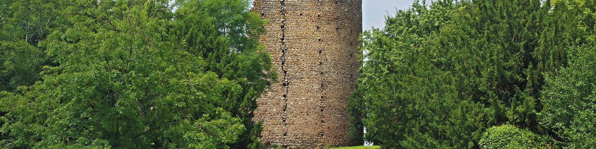Fréteval (Loir-et-Cher) Le château féodal de Fréteval. Le donjon. Il est construit au point culminant du plateau qui domine le Loir. Le donjon est directement assis sur le sol naturel. La construction du donjon est voisine de 1090 et la date de destruction du donjon proche de 1428-1429. Un examen approfondi montre que le donjon a été construit d'un seul jet. Architecture du donjon. Innovation pour l'époque, le donjon est cylindrique. Le diamètre à la base est de 15,60 mètres. Sa hauteur de 27,50 mètres, y compris 1,50 mètre de fondations. Les matériaux sont tous d'origine locale ou proche : silex, poudingue, grison*, craie tuffeau et calcaire de Beauce. Le liant est un mortier de chaux. La couverture était vraisemblablement de bardeaux de bois à l'origine, puis de tuiles. La muraille est en maçonnerie fourrée*. La construction a été réalisée à l'aide d'échafaudages successifs posés sur des boulins* engagés dans des trous dans la murailles. On observe seize rangée de trous de boulins espacées d'environ 1,10 mètre. L'alignement vertical des trous de boulins amène une faiblesse de la muraille. Le donjon comprend quatre niveaux: Le rez de chaussée, complètement aveugle avec un sol de mortier posé sur le sol naturel. Le premier étage avec la porte d'accès, éclairé par quatre fenêtres. Le premier étage copossède une cheminée murale et un puits. Le deuxième étage, avec deux fenêtres qui subsistent. Une cheminée murale. Une galerie externe ceinturait cet étage qui devait être l'étage seigneurial. Une porte externe permet l'accès à la galerie. Le troisième étage, avec quatre fenêtres qui donnaient approximativement, comme le premier étage, sur les quatre points cardinaux. Vers le nord-ouest, la fenêtre a été en partie murée. Une partie du troisième étage a été détruite en 1982, emportant les vestiges d'une fenêtre. Les fouilles de la partie basse du donjon ont permis de mettre en évidence : un remplissage d'argile sur 4 m d'épaisseur pour une raison inconnue, des couches liées à une activité de cuisine sur la couche d'argile, des couches résultant de la destruction de la toiture avec présence de tuiles. grison : Le grison est une roche dure constituée d'un agrégat de cailloux siliceux soudés par un ciment ferrugineux donnant une couleur brun-rouille à l'ensemble. maçonnerie fourrée : cad constituée de deux murs montés en pierres entre lesquels était versé un mortier, voir simplement de la terre. boulins : pièces de bois horizontales engagées dans des trous du murs et sur lesquels on pose les planches de l'échafaudage. (D'après présentation sur place de Claude Leymarios, archéologue) Castle Fréteval. The keep was built on the highest point of the plateau overlooking the Loir river. Construction of the tower is around 1090 and the date of destruction of the dungeon near 1428-1429. Innovation for the time, the keep is cylindrical. The base diameter is 15.60 meters. Its height of 27.50 meters, including 1.50 meters of foundations. The materials were taken from the nearby region : Silex puddingstone, limestone. The mortar is a lime mortar. the wall is filled masonry. The roof probably conical was made with tiles. The Dungeon consists of four levels.