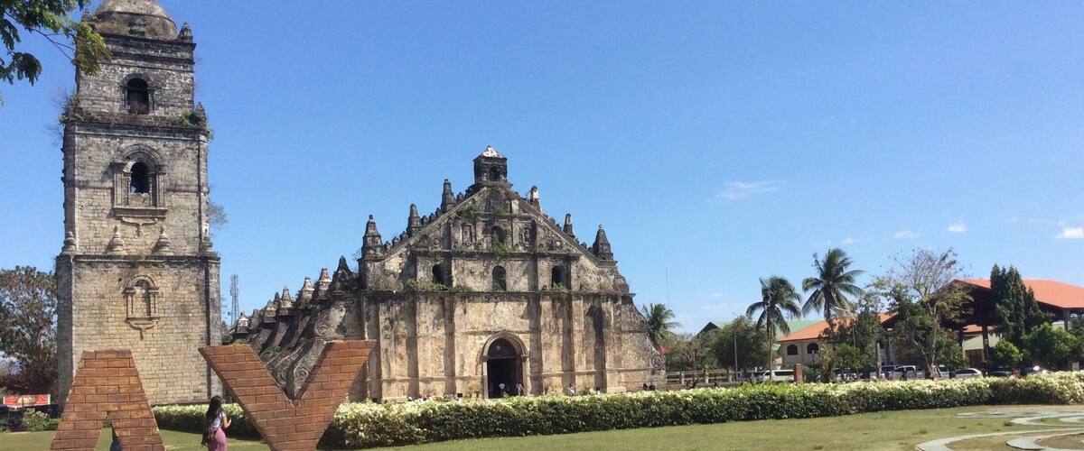 A historic church with a bell tower and a statue in the foreground.