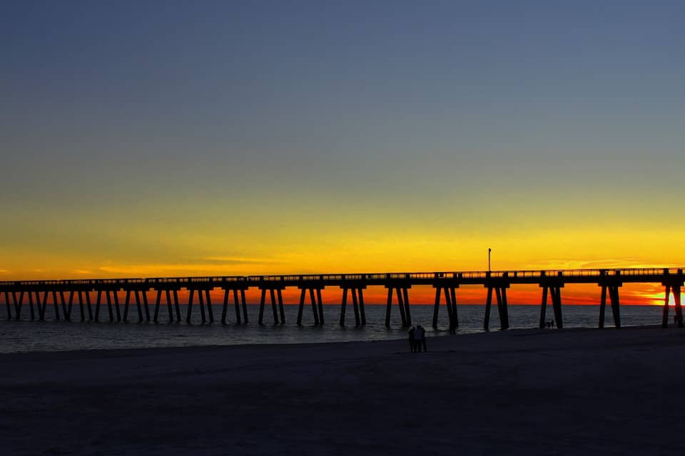 A pier extending into the ocean at sunset.