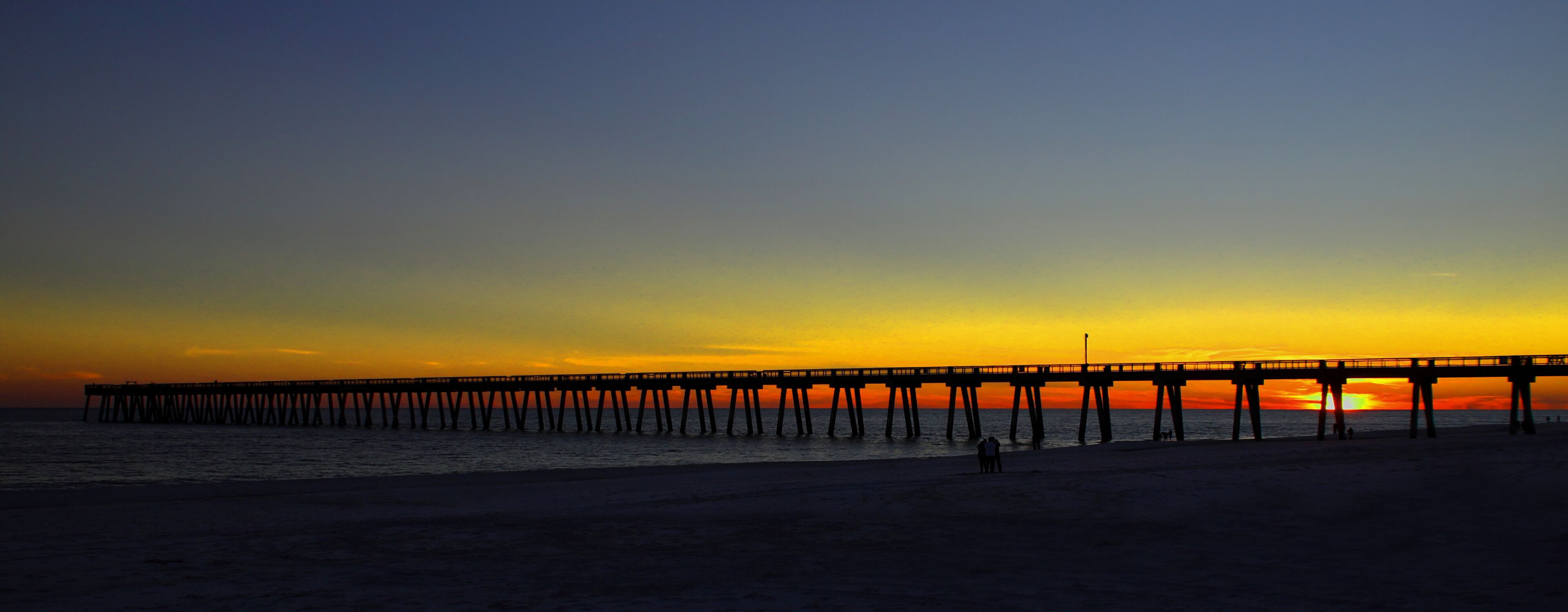 A pier extending into the ocean at sunset.