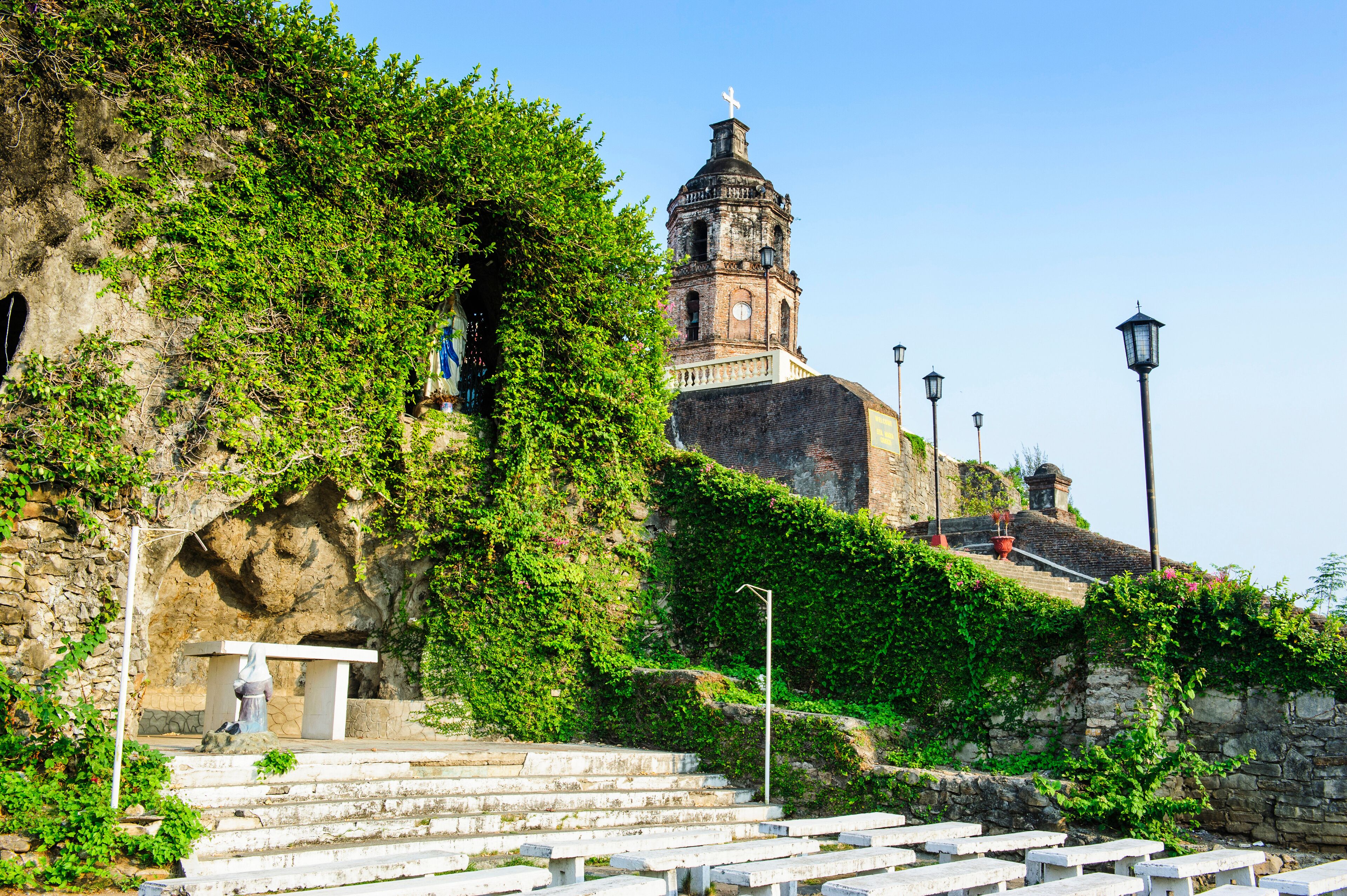 A stone staircase leading up to a church with a bell tower, surrounded by greenery.