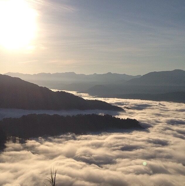 A mountainous landscape with a valley below, surrounded by clouds.