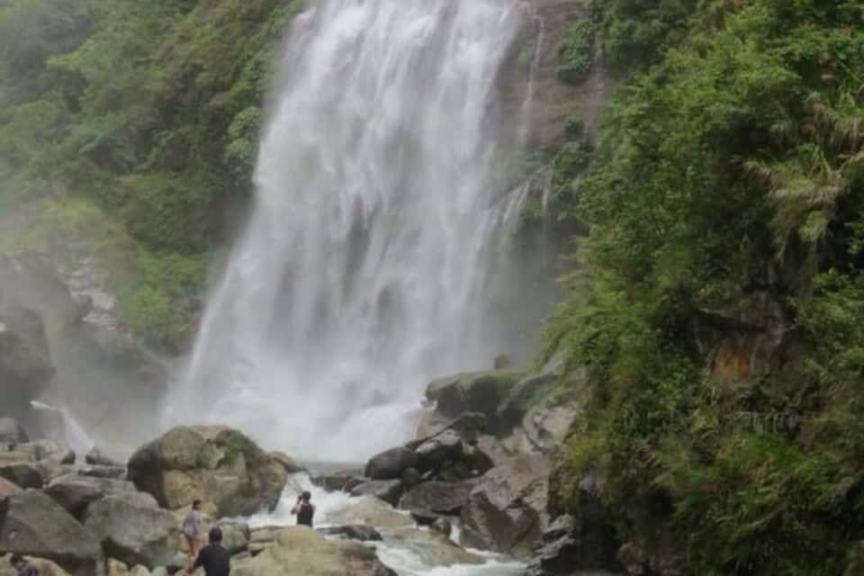 Unes cascades altes que flueixen per un costat de pendent verd i exuberant.