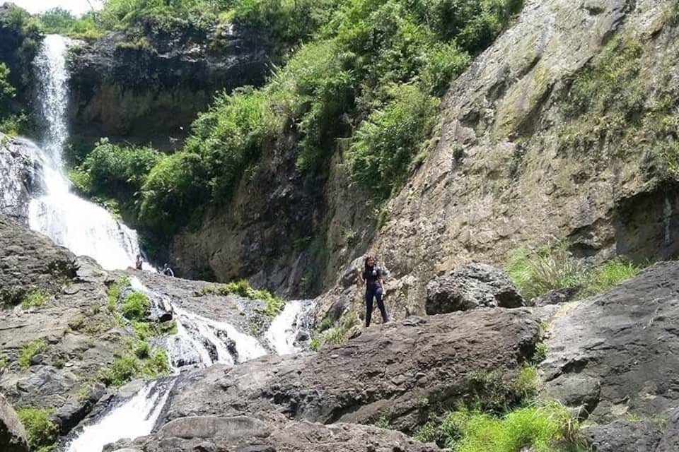 Una cascada se precipita por un acantilado rocoso rodeado de vegetación exuberante.