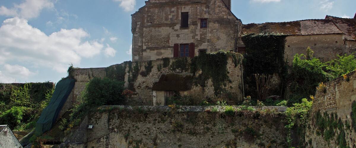 An old stone building with ivy and a steeply pitched roof.
