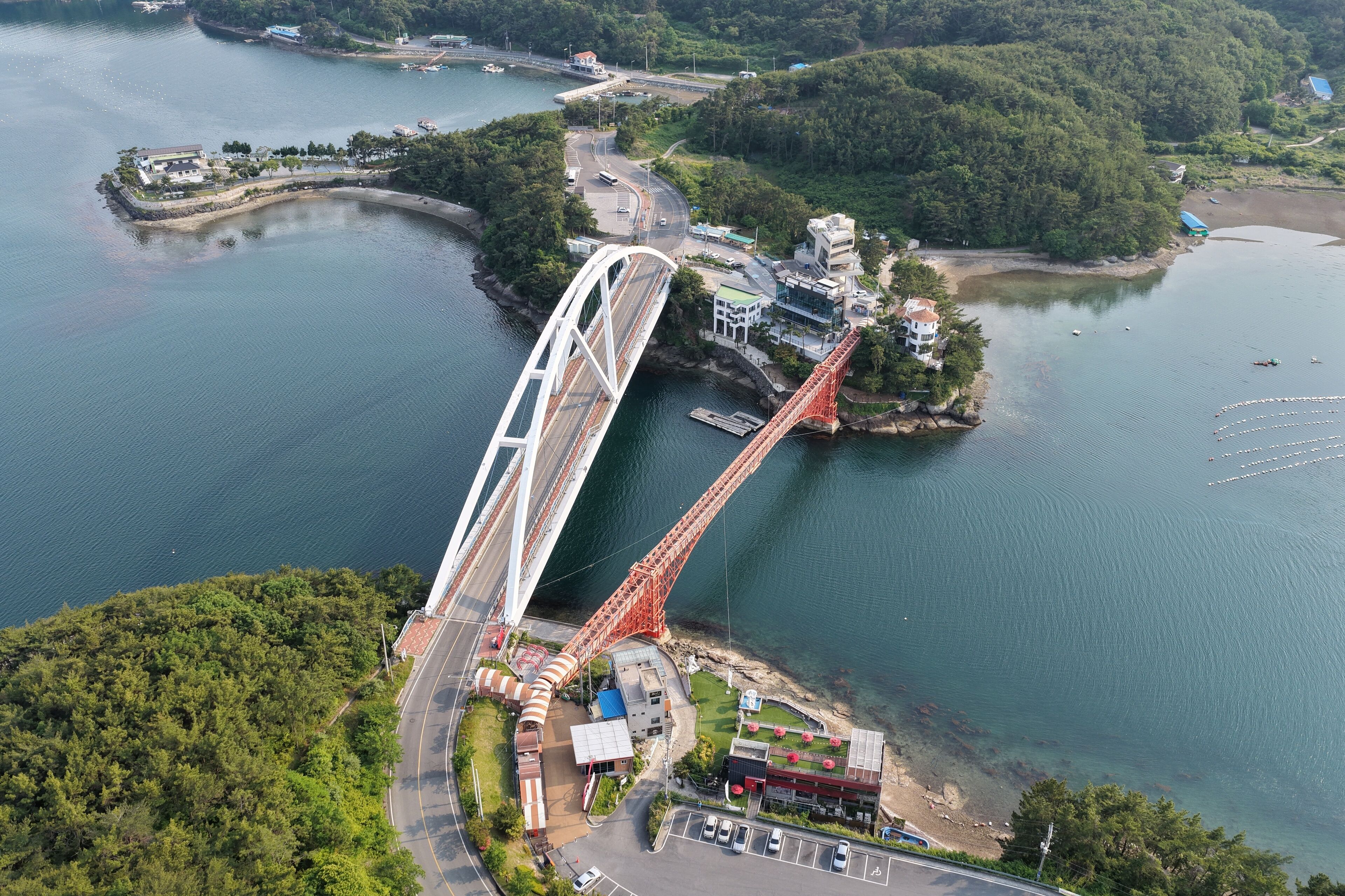 A large suspension bridge spanning a river, surrounded by lush greenery and a small island with buildings.