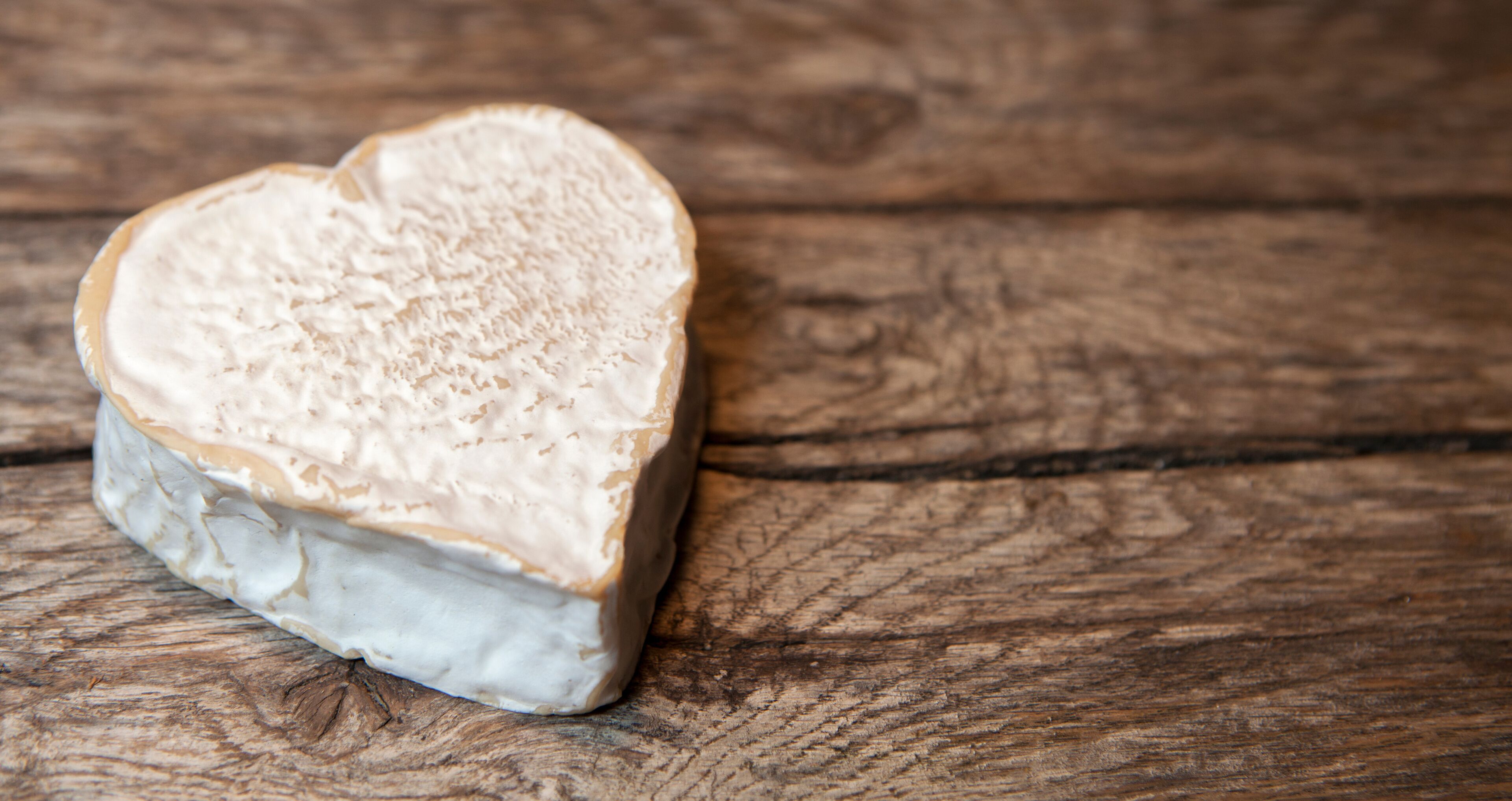 A heart-shaped cheese on a wooden surface.
