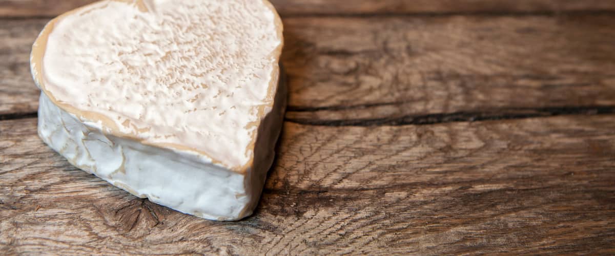 A heart-shaped cheese on a wooden surface.