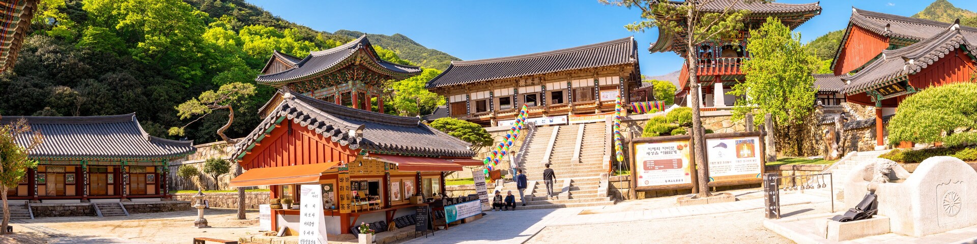 Traditional Korean architecture with wooden buildings and a stone monument.