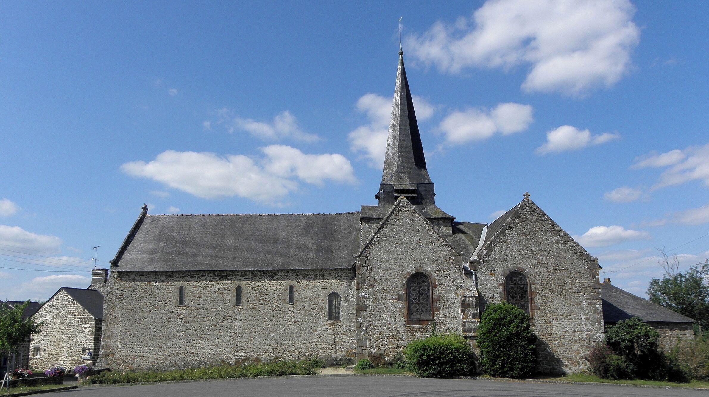 A stone church with a tall spire and arched windows.