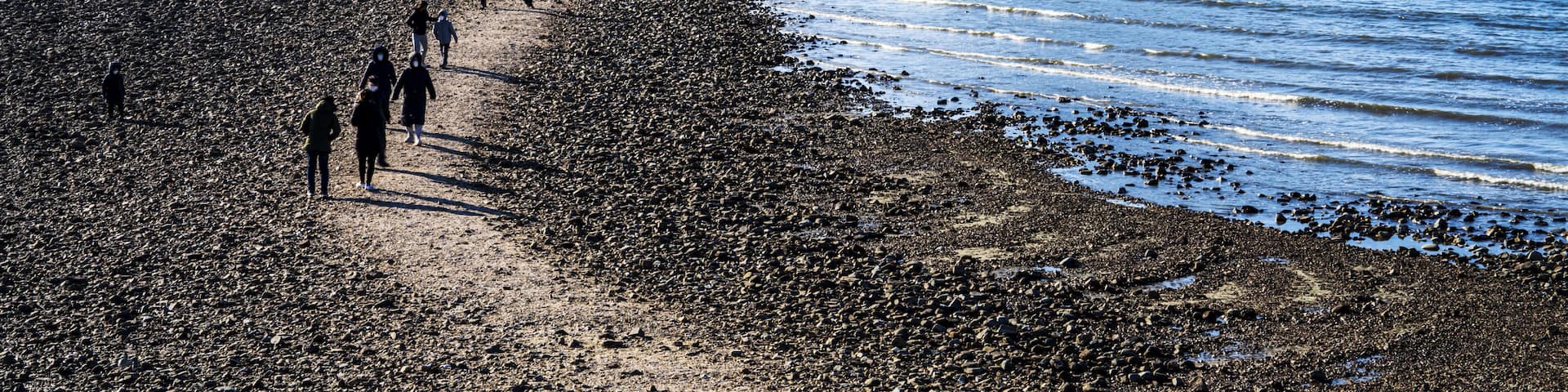 Seung-eon-ri, Anmyeondo Island, Taean-gun, Chungcheongnam-do, South Korea - April 13, 2021: Tourists are walking on sea road at low tide at Kkotji Beach against two rock islands and horizon