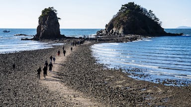 Seung-eon-ri, Anmyeondo Island, Taean-gun, Chungcheongnam-do, South Korea - April 13, 2021: Tourists are walking on sea road at low tide at Kkotji Beach against two rock islands and horizon
