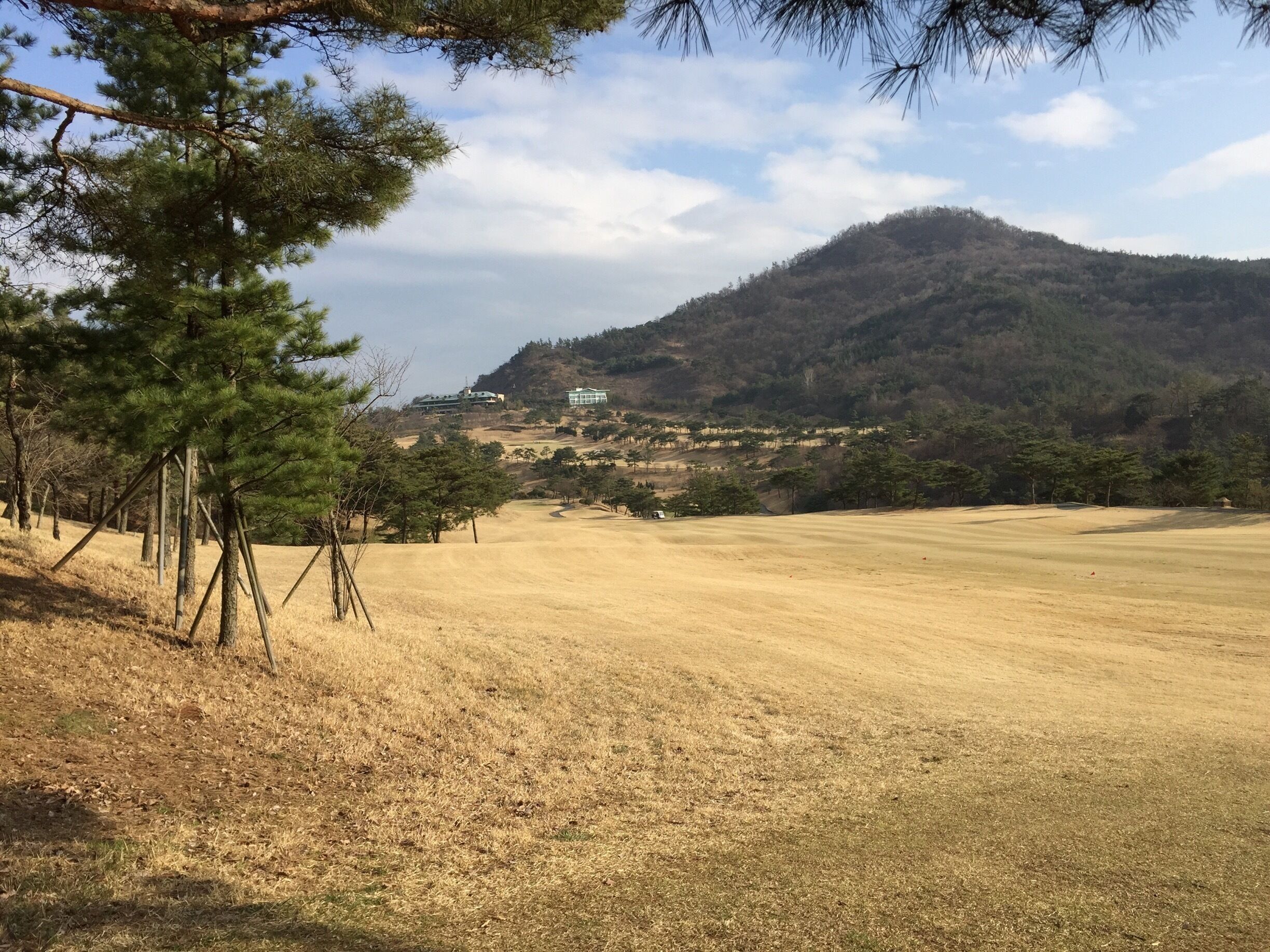 A golf course with a mountain in the background and a building on the hillside.