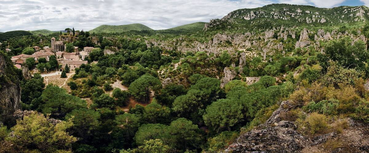 A village nestled in a valley surrounded by lush greenery and rocky hills.