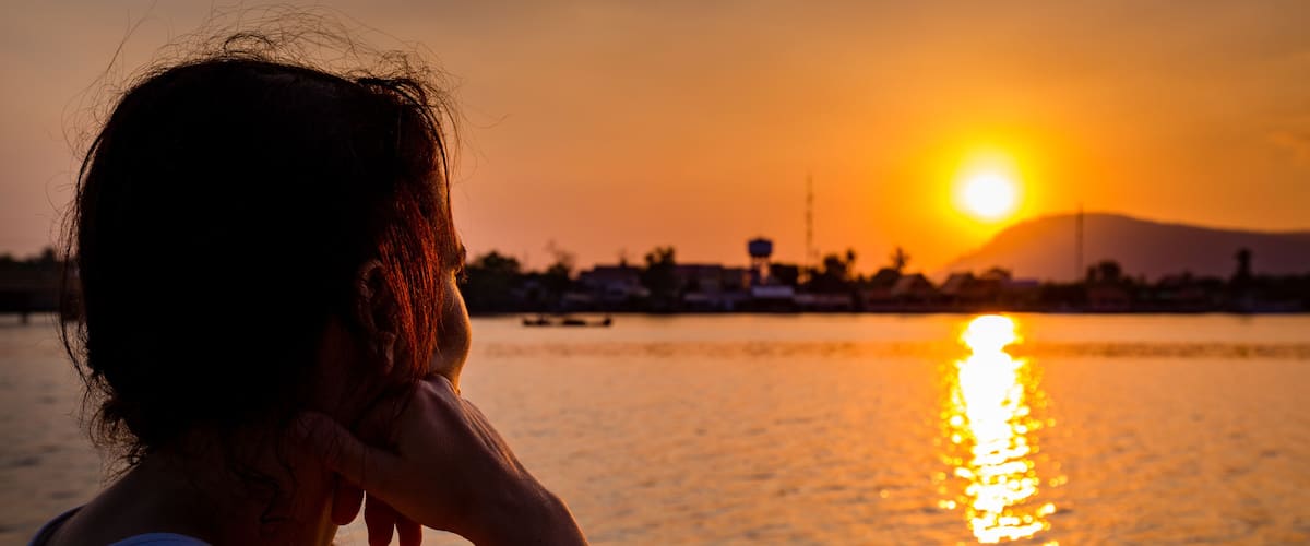 Girl looking into the sunset at a river in Kampot, Cambodia