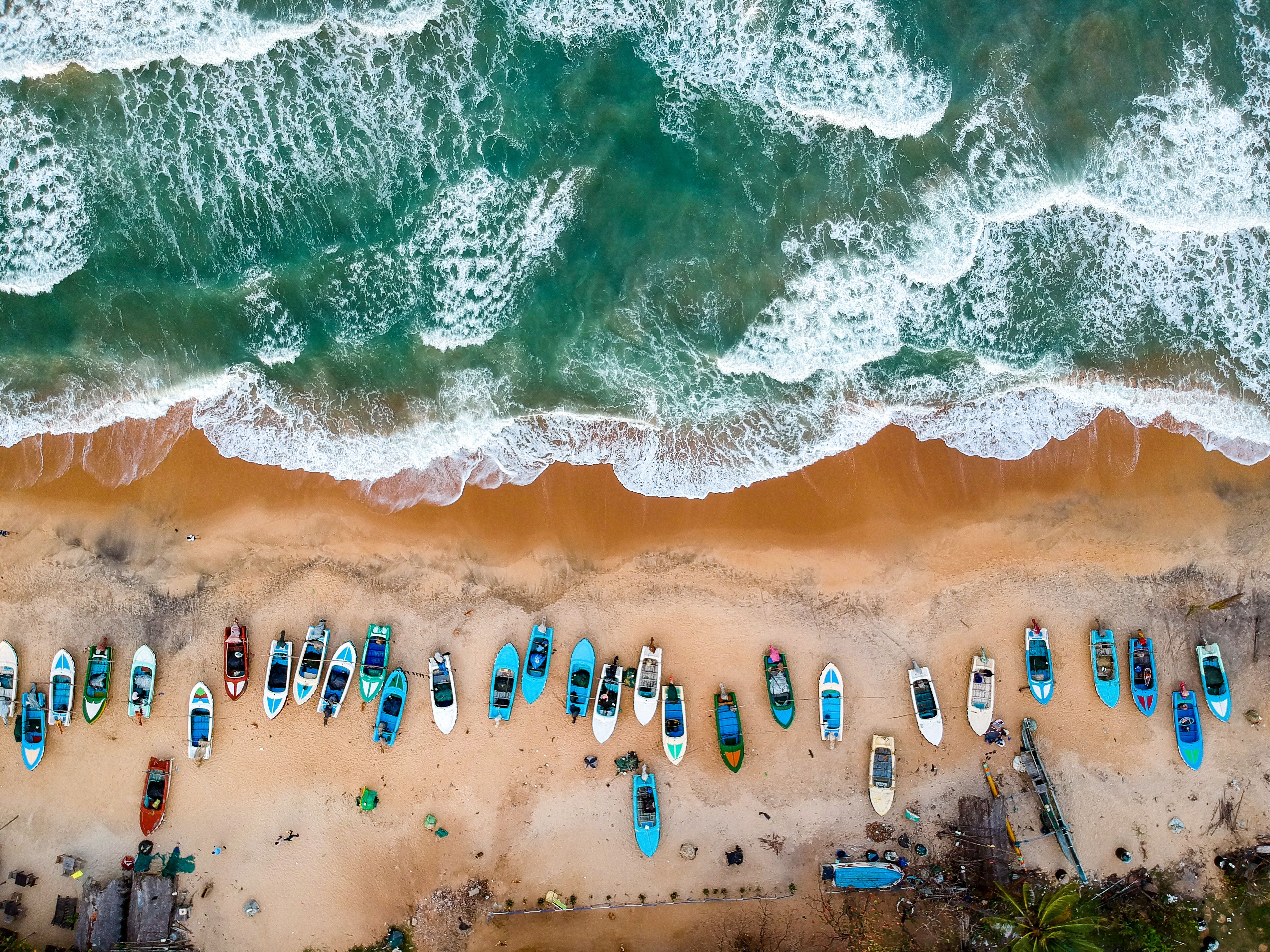 An aerial view of a beach with rows of boats and waves crashing onto the shore.