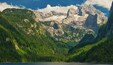 Un paisaje montañoso con un glaciar y bosques densos.