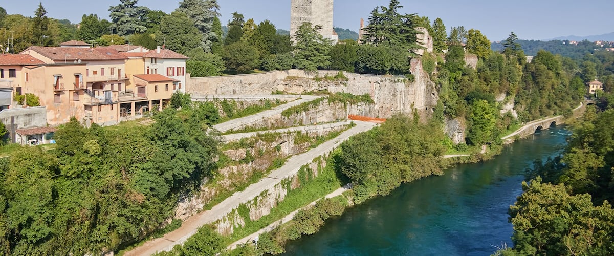 A river with a bridge, a tower, and terraced vineyards.