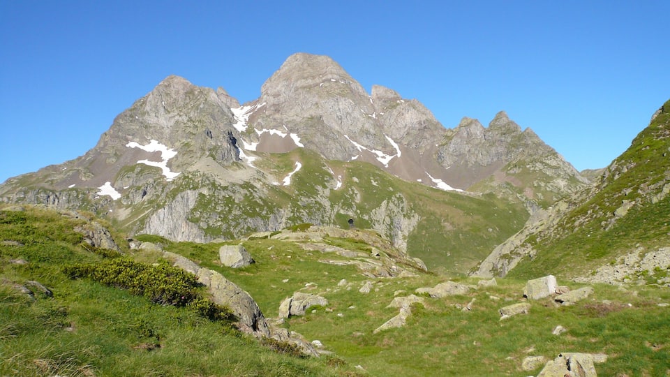 A mountainous landscape with rocky peaks and patches of snow.